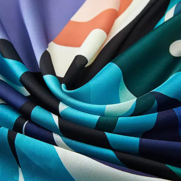 Pelican Large Square Silk Scarf | Blue (90 × 90 cm) showing smooth silk fabric draped with abstract blue, teal, black, and white patterns.