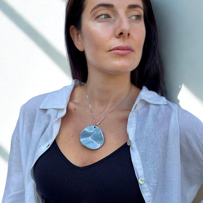 Close up of model wearing Perla light blue ceramic pendant necklace with silver chain