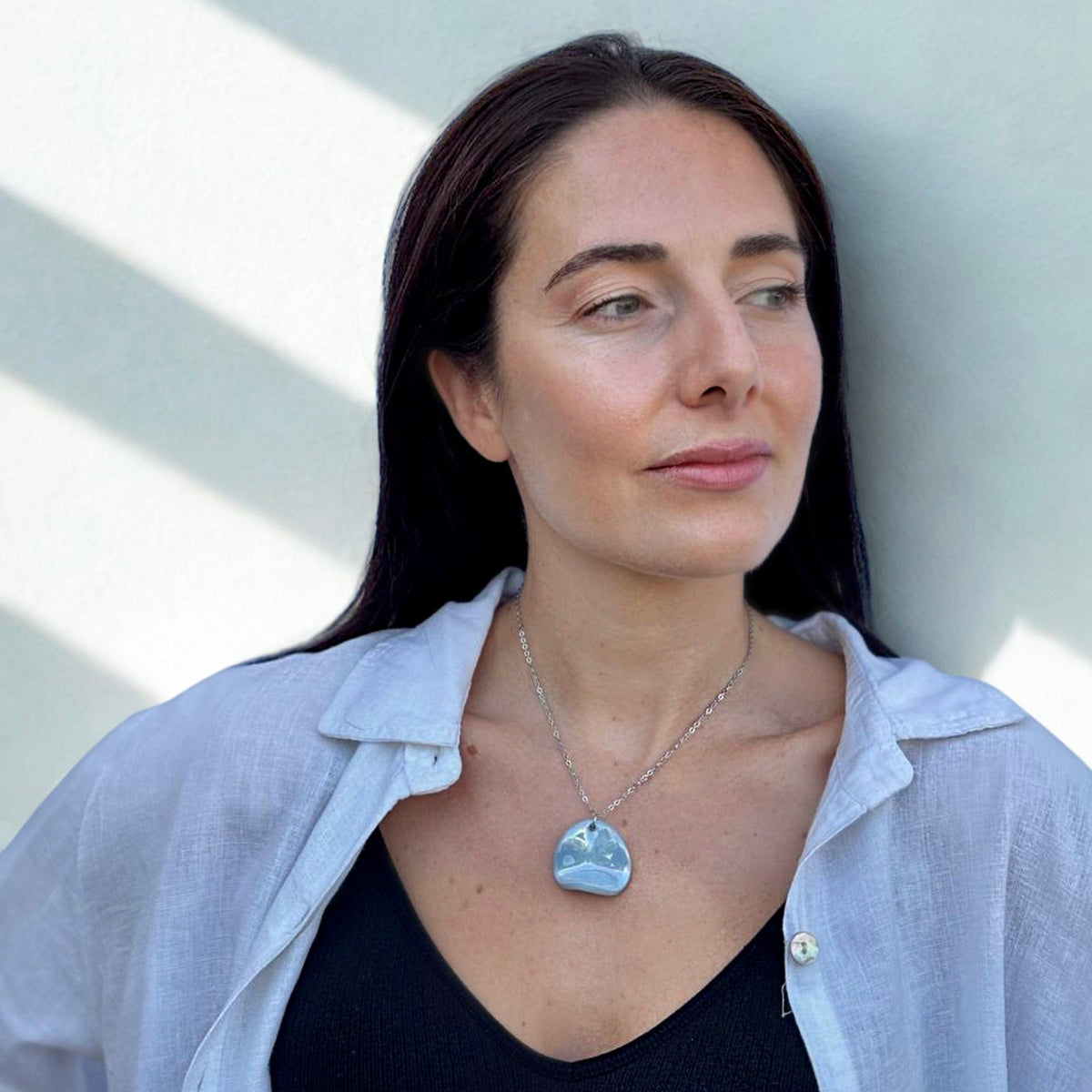 Front view of the light blue ceramic pendant necklace resting on the model's chest