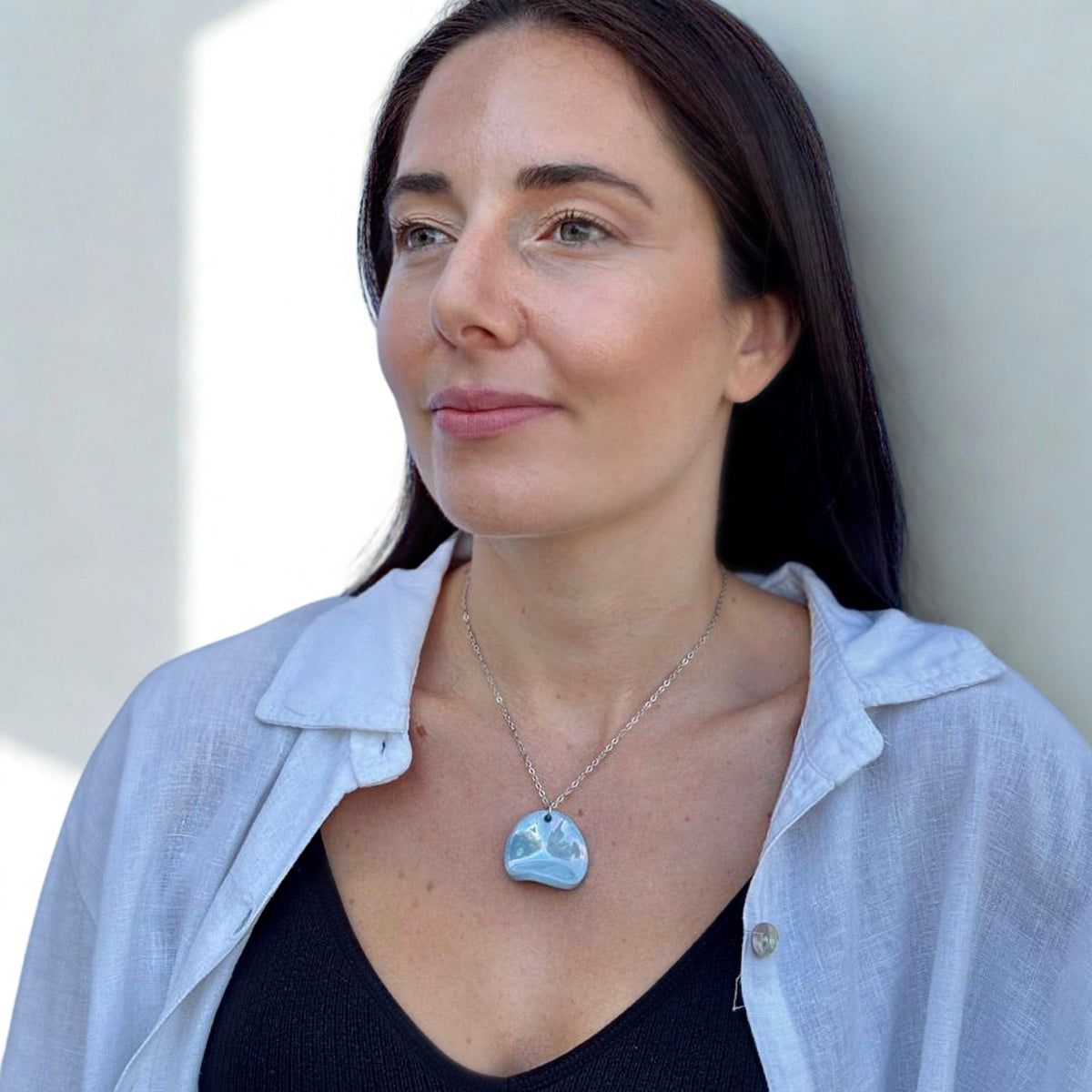 Model wearing Perla handcrafted light blue ceramic pendant necklace with a silver chain