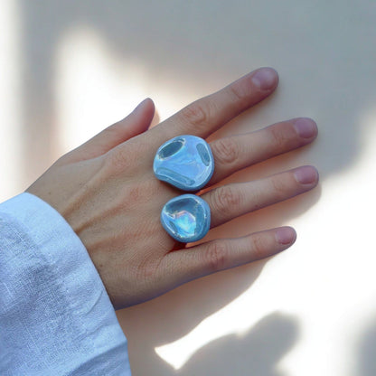 Two azzurro pearl ceramic rings worn on a he against a pale background.