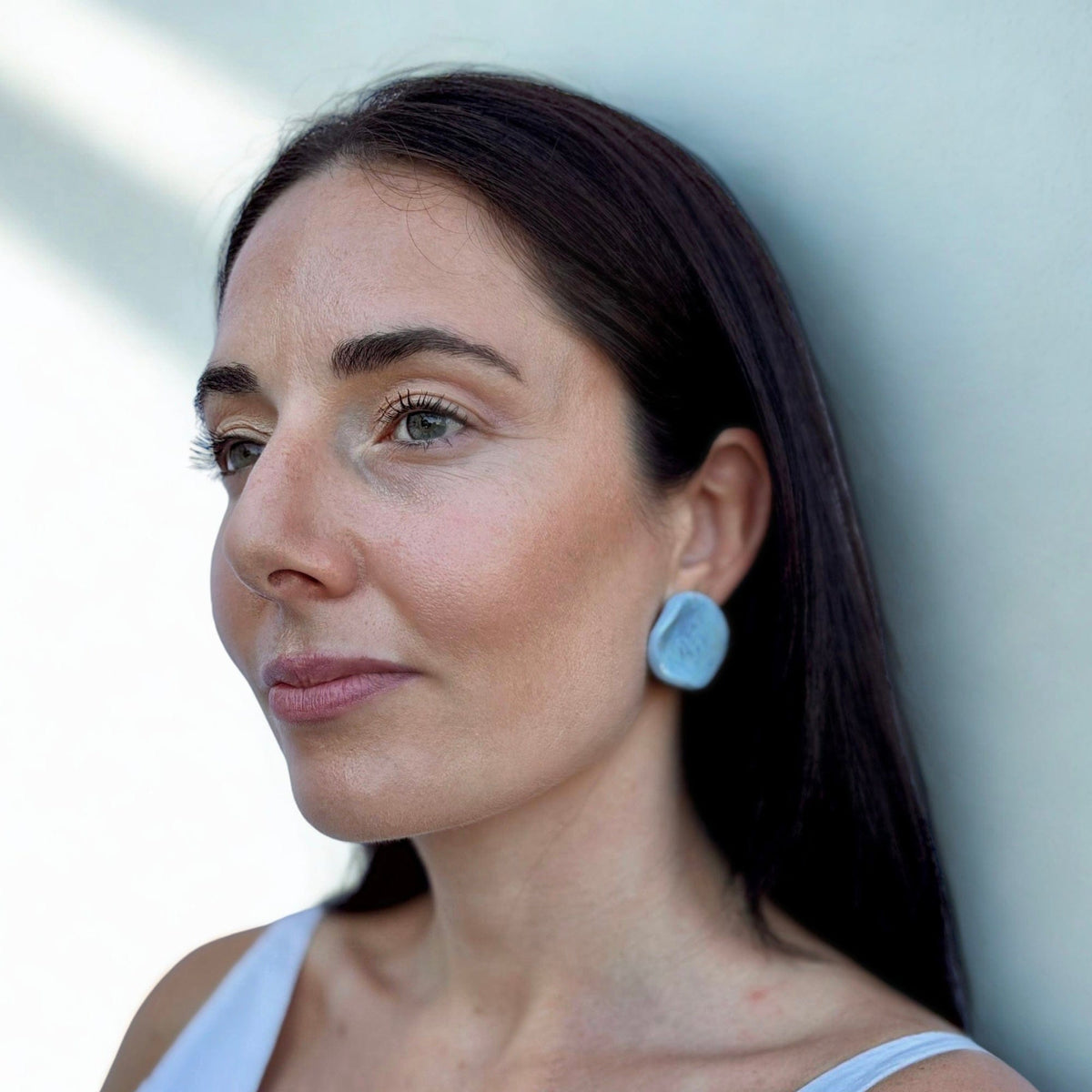 Portrait of a donna con a azzurro ceramic pearl stud earring from the Perla collection