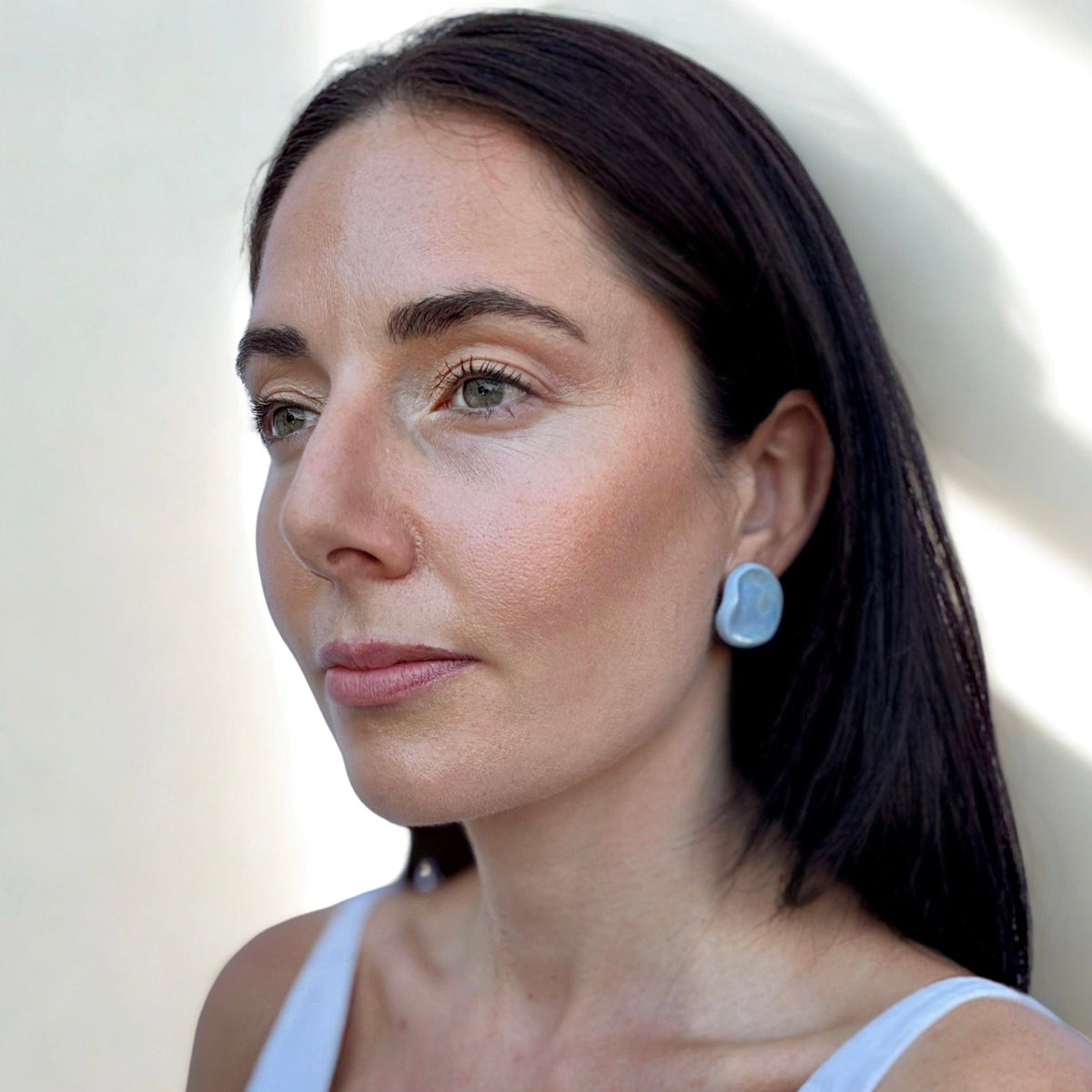 Primo piano of a blu ceramic pearl stud earring on a woman's ear from the Perla collection
