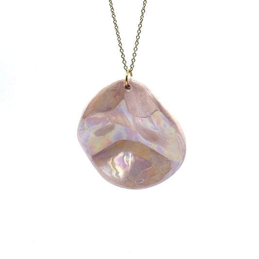 Pearl-rosa ceramic pendant necklace on a gold chain against a bianco background