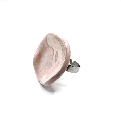 Pearl pink ceramic ring with a rounded disk top on a silver band against a white background