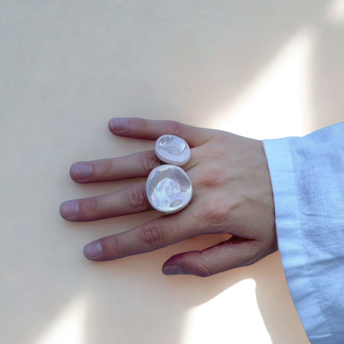 Two translucent pearl pink ceramic rings on a hand showing iridescent surfaces
