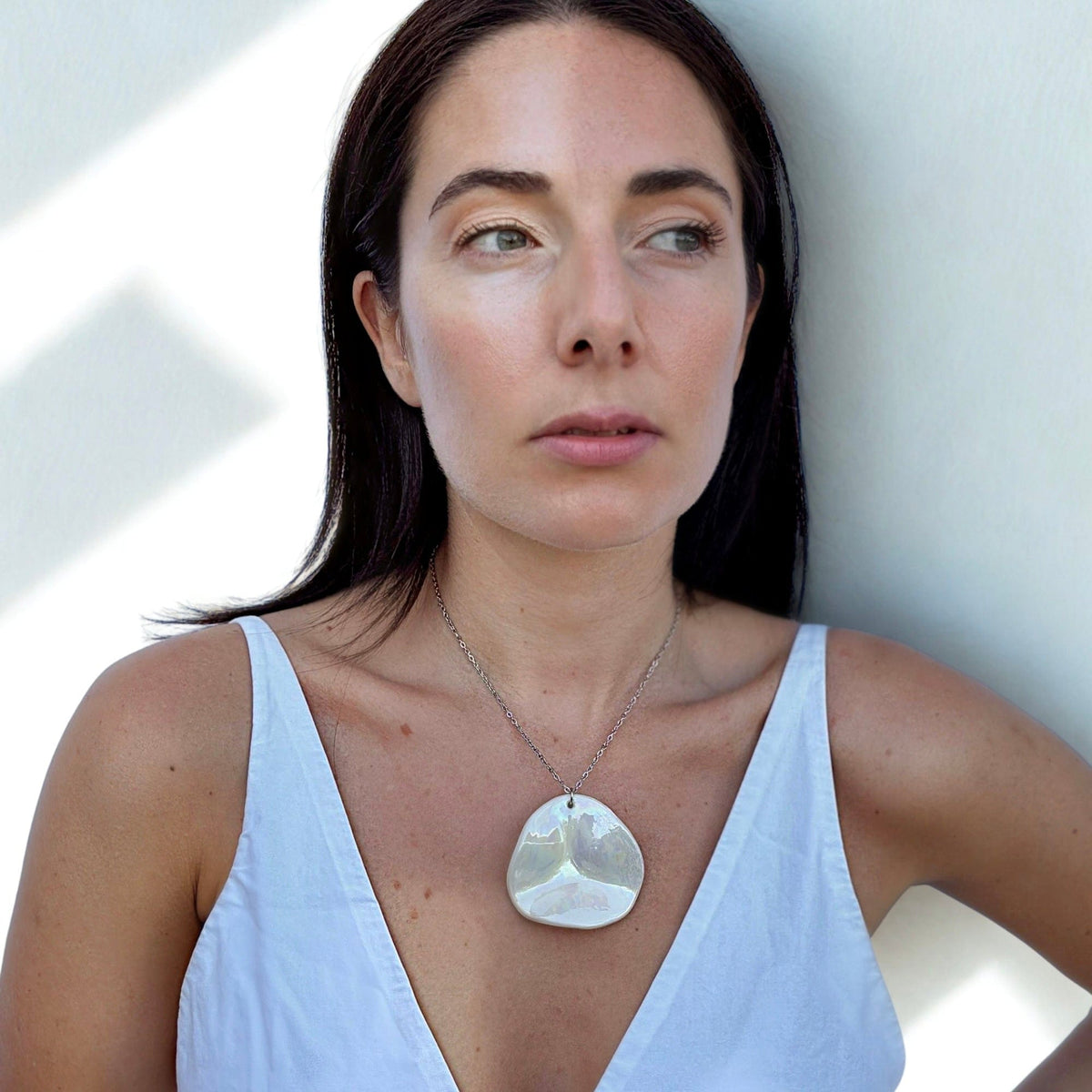Mujer con a large pearl-white handcrafted ceramic necklace from the Perla collection.