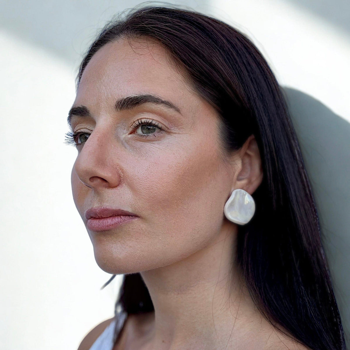 Model trägt a large pearl white ceramic earring on her ear