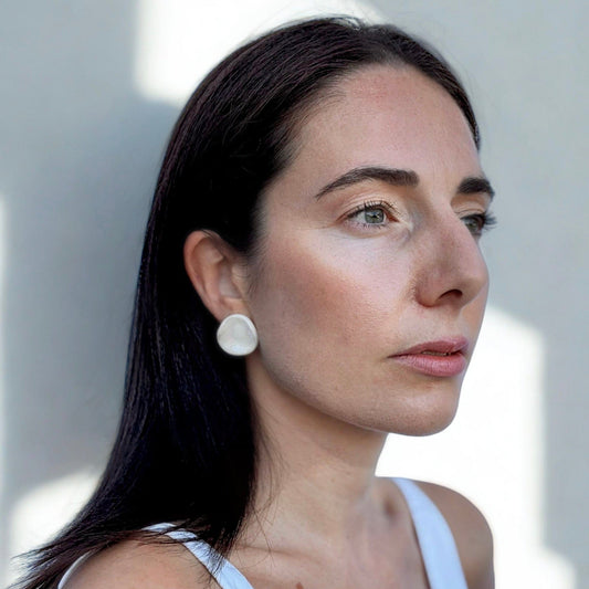 Vista lateral of a mujer con a pearl white ceramic stud earring