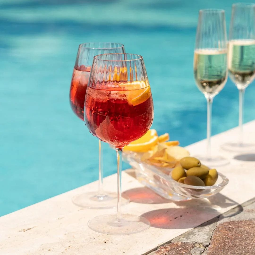 Two Rotweingläser with a red cocktail and citrus wedge on a poolside table