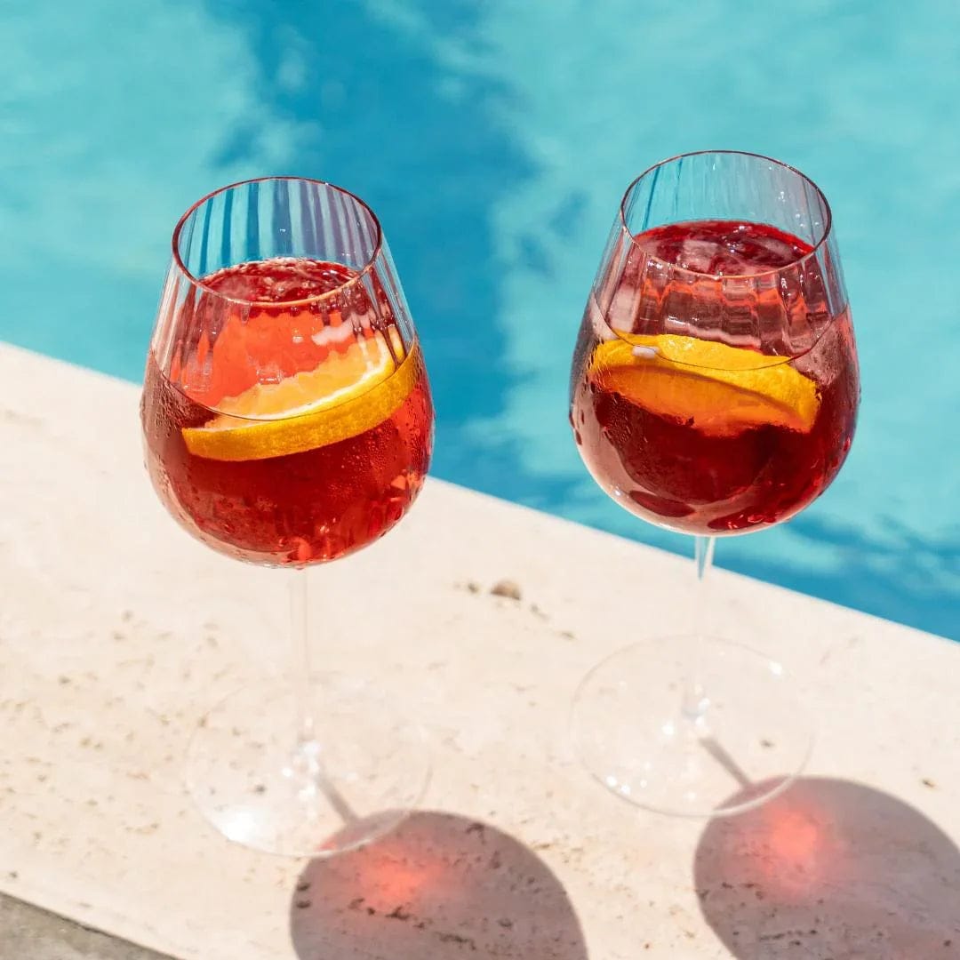 Two Round Up Altrosa Rotweingläser with citrus slices in a Szene am Pool.