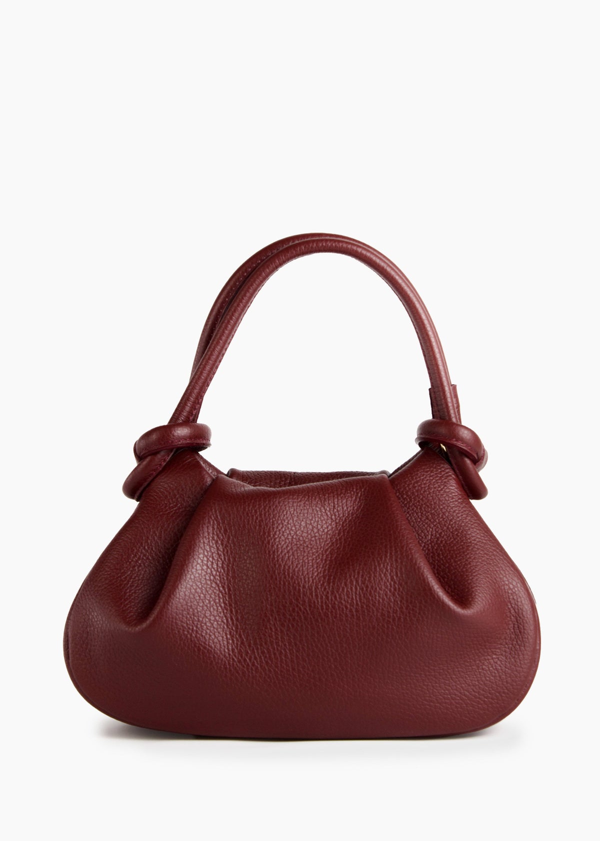 A small pebbled leather handbag in deep burgundy red, featuring a top handle with knotted details at the sides, set against a plain white background.