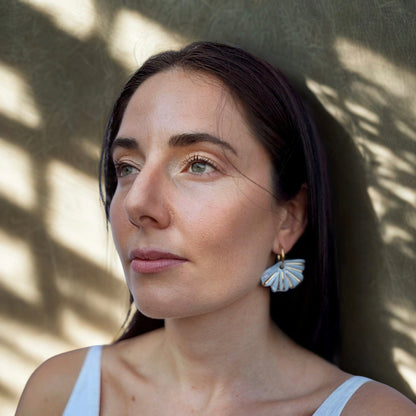Selene handcrafted azul-claro ceramic dangle earrings with golden details worn by a woman