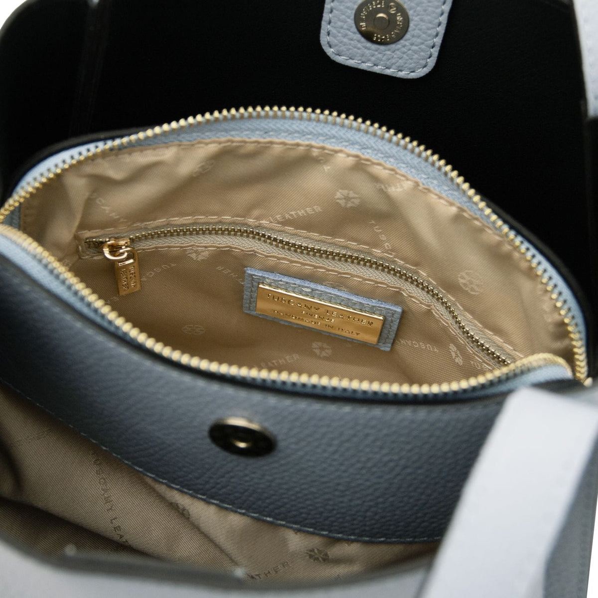 Inside view of the Soave handbag with beige lining, zip pocket and a gold label plaque.