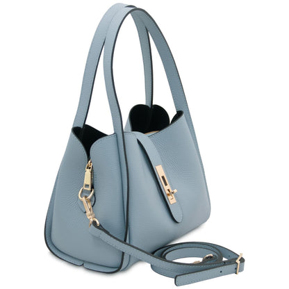 Three quarter view of light blue pebble leather handbag with detachable strap and gold hardware