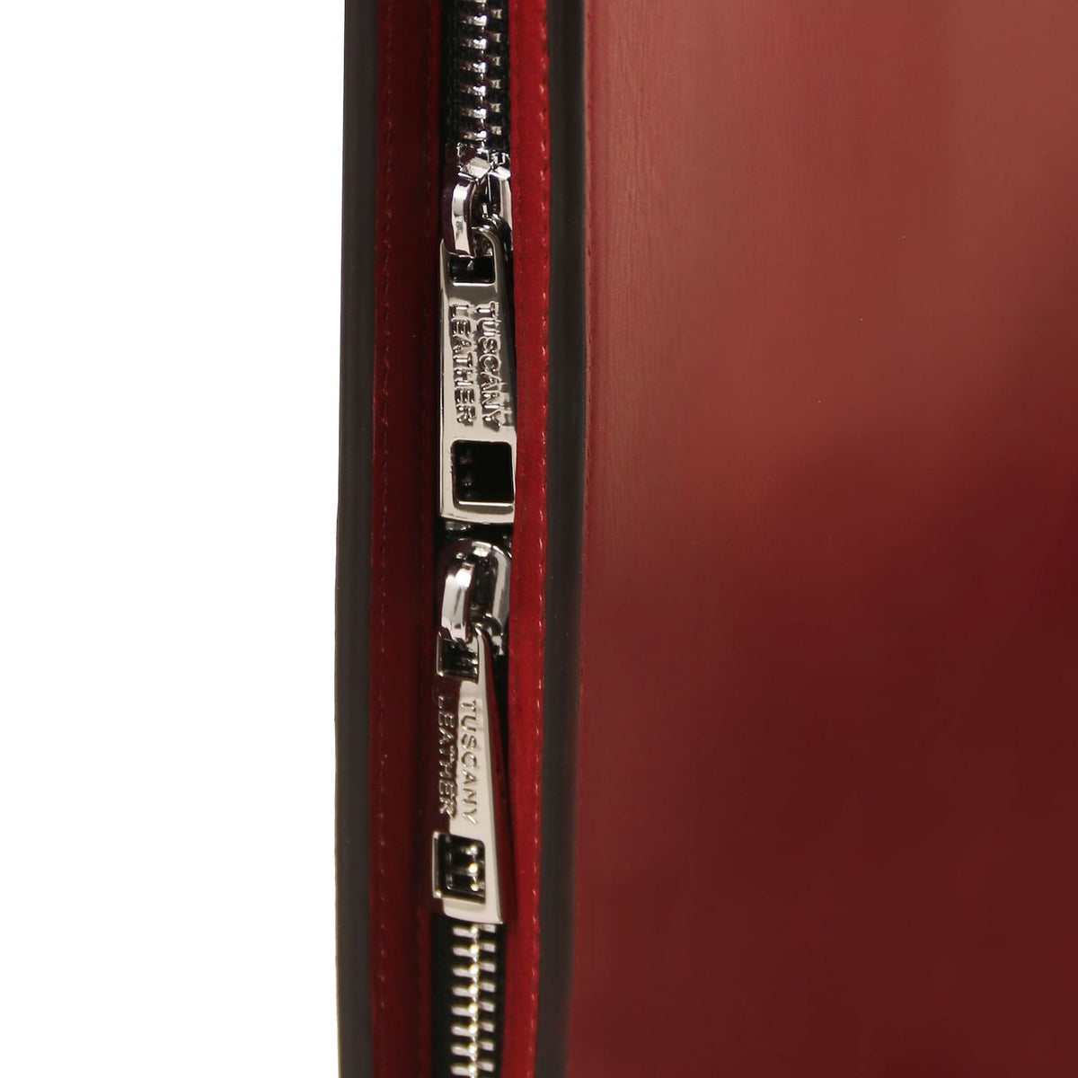 Primer plano of a silver zipper on a red leather document case.