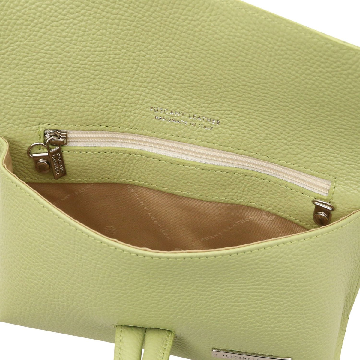 Gros plan of vert citron textured leather bag interior showing a poche zippée and doublure cognac
