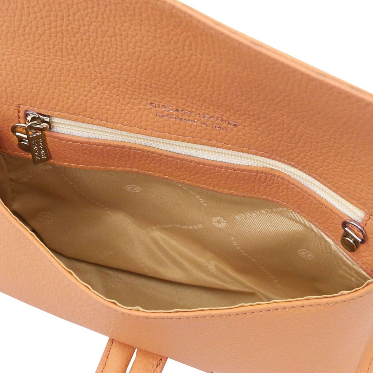 Interior of cognac cuir grainé foldover clutch with poche zippée and doublure beige.