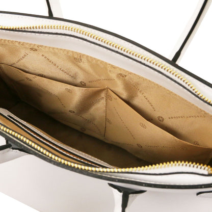 Vista interior of leather handbag showing beige forro de tela with logo pattern and internal bolsillo abiertos, cremallera dorada closure visible.