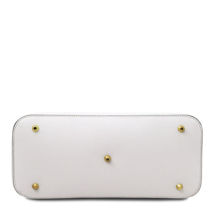 Vista inferior of a white leather handbag with five brass protective feet and detailed stitching along the edges.