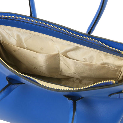 Abierto view of blue leather handbag showing beige fabric interior with stitched pockets and cremallera dorada closure