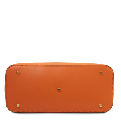 Vista inferior of a structured cuero leather handbag showcasing gold-tone metal feet and detailed stitching.