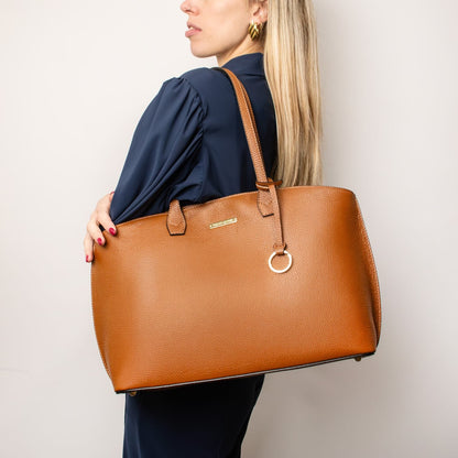 Cognac cuir grainé cabas shopping carried over the shoulder by a model in a bleu marine blouse