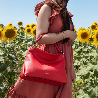 Modella con a rosa dress carries a rosso TL Bag through a sunflower field