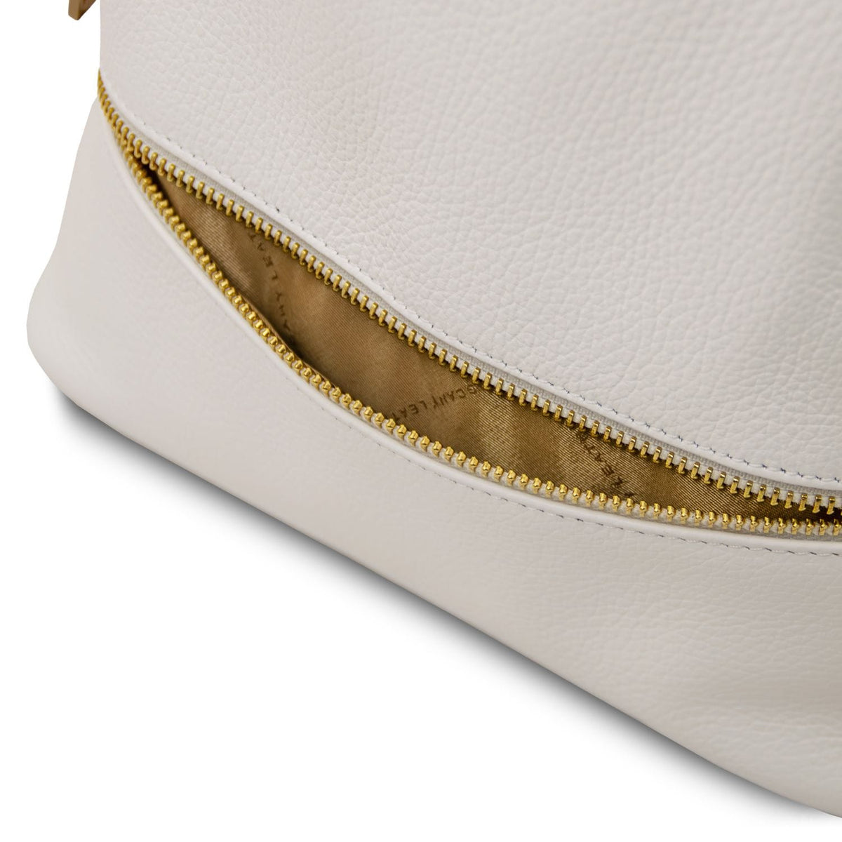 Gros plan of a fermeture zippée dorée along the side seam of the white leather bag