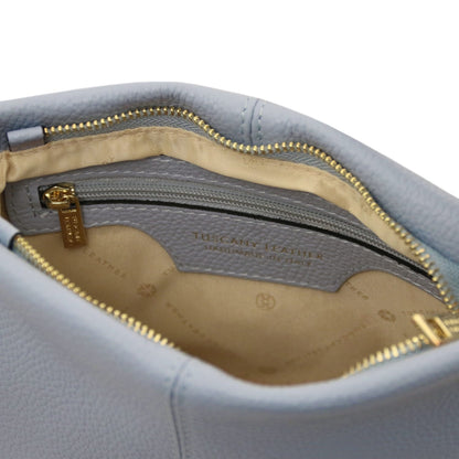 Nahaufnahme of hellblau weiches Leder shoulder bag interior showing beige Stofffutter, Reissverschlusstasche, and gold-tone zipper pull.