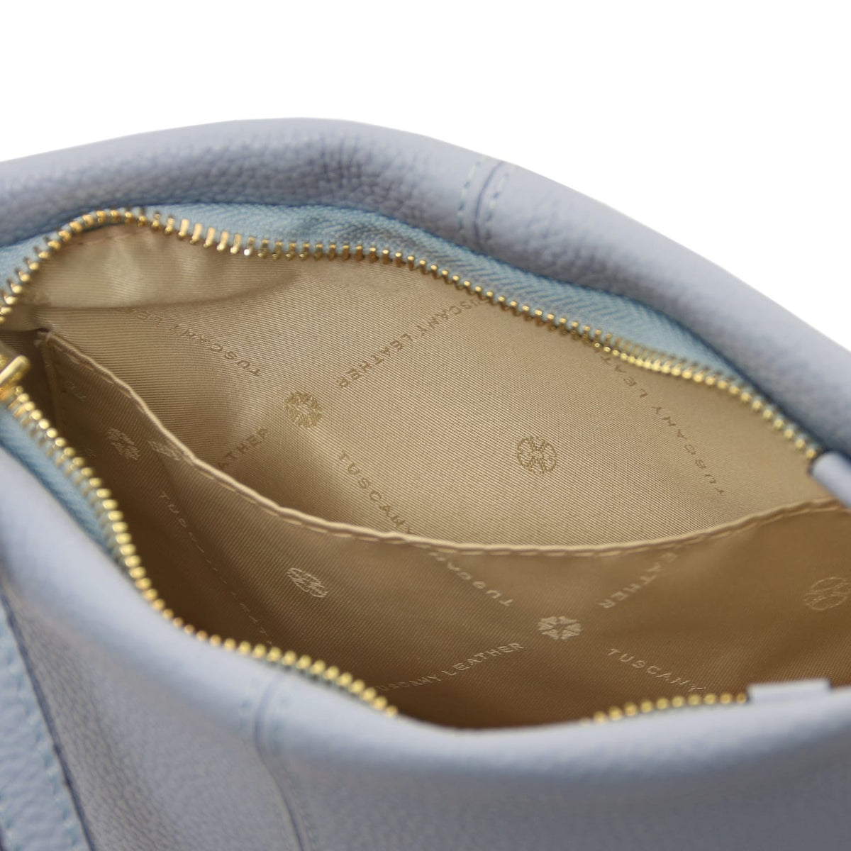 Geöffnetes view of soft pebbled hellblau leather shoulder bag showcasing beige Innenfutter with logo print and open pocket detail.
