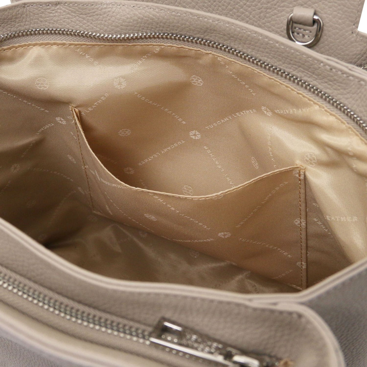Close-up of beige Italian leather handbag interior showing silk fabric lining and internal slip pocket with zip closure edge.