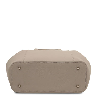 Bottom view of a taupe Italian leather handbag with pebbled texture and protective metal feet on the base.
