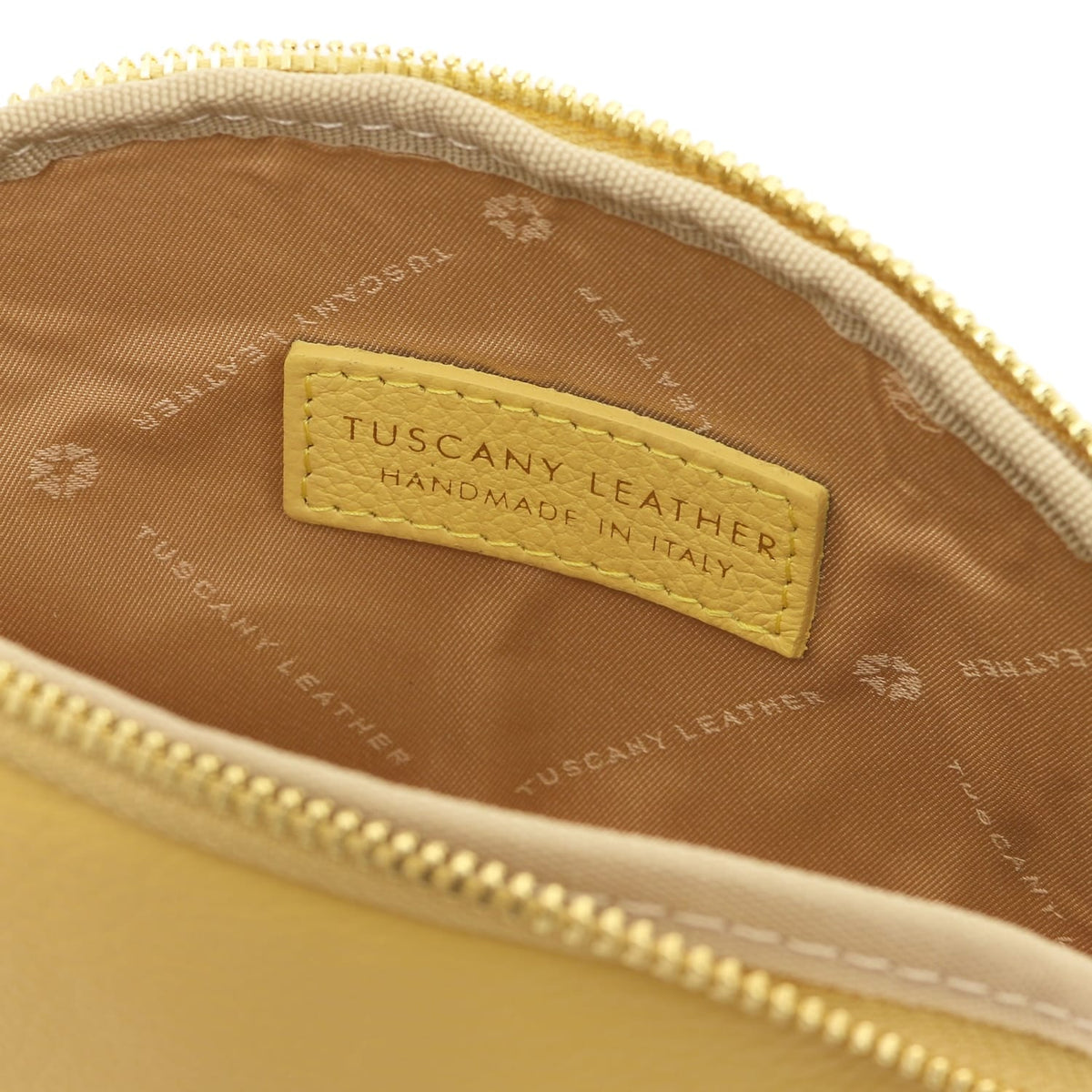 Primer plano of piel suave toiletry case interior showing forro de tela and stitched Tuscany Leather label inside zipper opening.