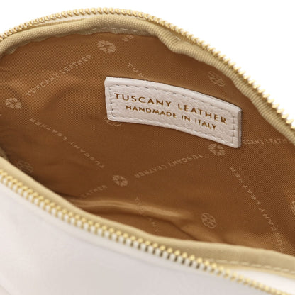 Primer plano of beige leather toiletry case interior featuring branded forro de tela and stitched Tuscany Leather label inside zipper opening.