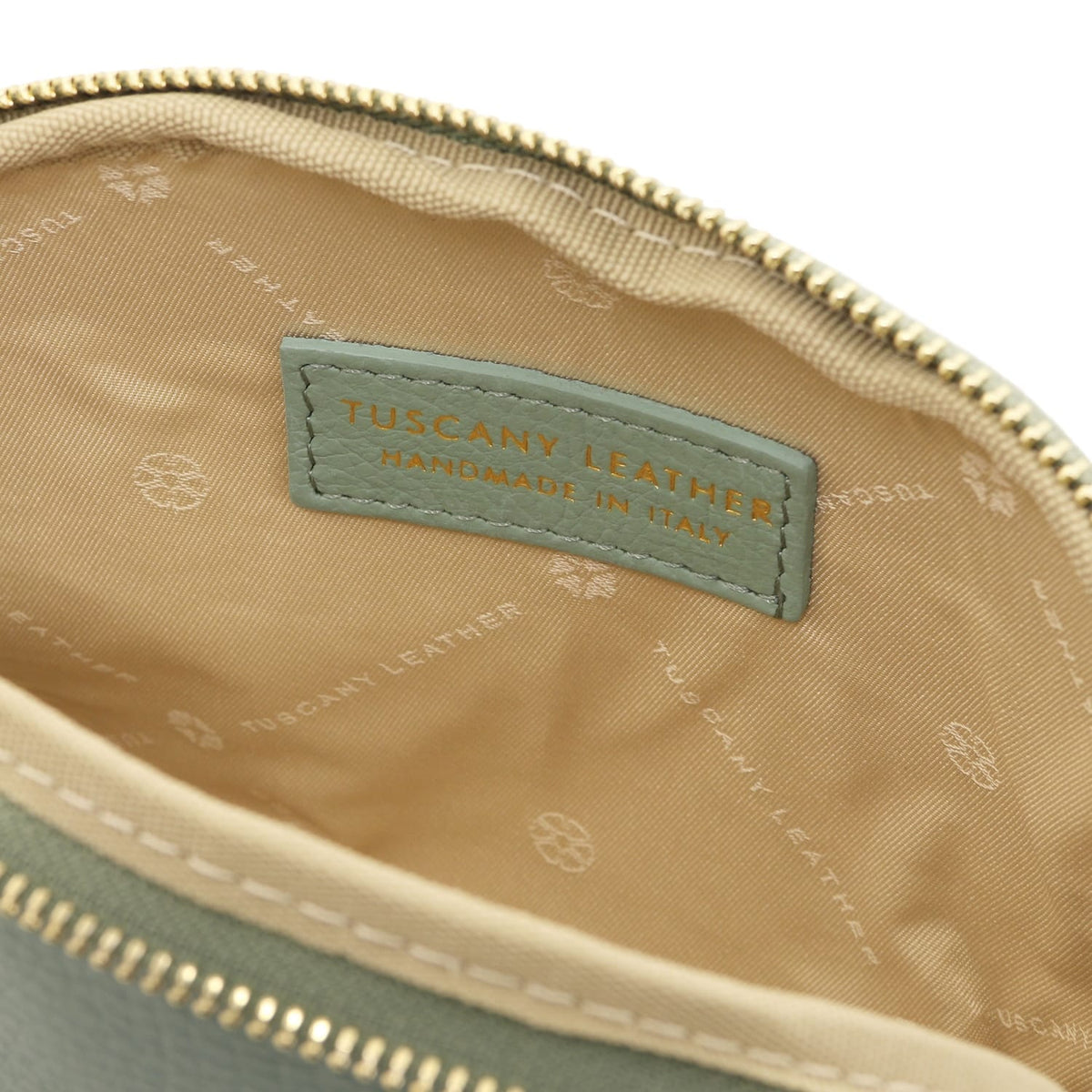 Primer plano of beige fabric interior with Tuscany Leather label stitched inside piel suave toiletry case.