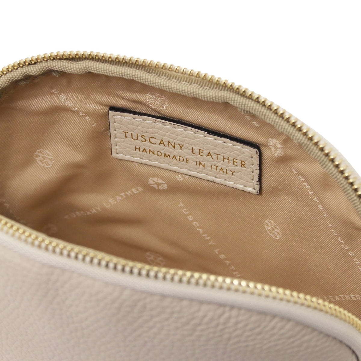 Primer plano of beige piel suave toiletry case interior with forro de tela and Tuscany Leather "Handmade in Italy" label.