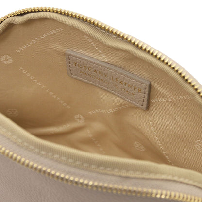 Primer plano of soft beige leather toiletry case interior featuring branded forro de tela and leather label inside zipper opening.