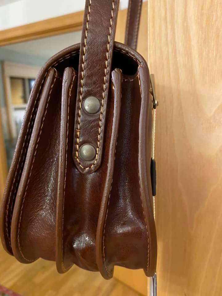 Isabella - Lady leather saddle bag | TL9031 in brown Italian leather with contrast stitching and metal rivet details on the side view